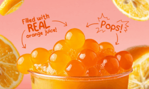 A close up of orange popping boba in a drink filled with real orange juice, highlighting the juicy burst and playful texture, perfect for milk tea shops in the Philippines.